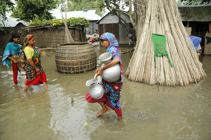 Flood victims return their temporary shelters in an embankment after collecting drinking water near ...