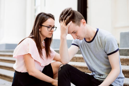 Female student calms her male friend. Teenager is upset, sits on stairs and don`t wont anything, his...