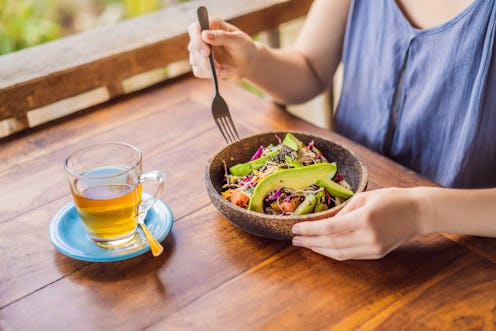 Woman eating quinoa salad at a wooden table outside. Here's what happens to your body when you stop ...