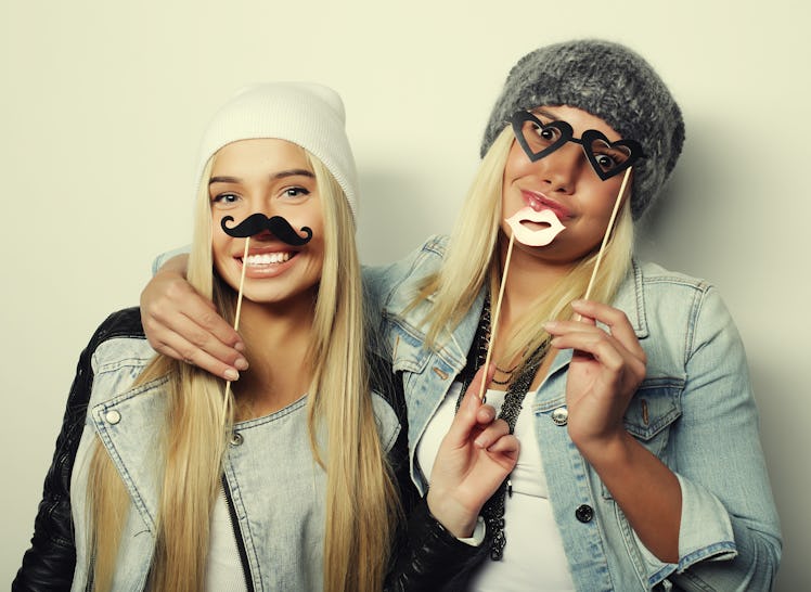 Two blonde friends pose in their simple Halloween costumes in front of a white background.