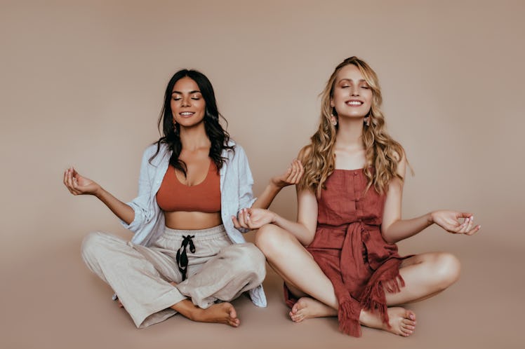 Two friends do yoga in a studio and meditate together.