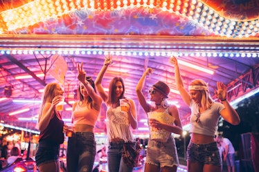 Five friends dance in an amusement park with kettle corn and drinks.