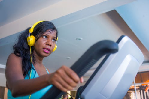 indoors gym portrait of young attractive and concentrated black afro American woman with headphones ...