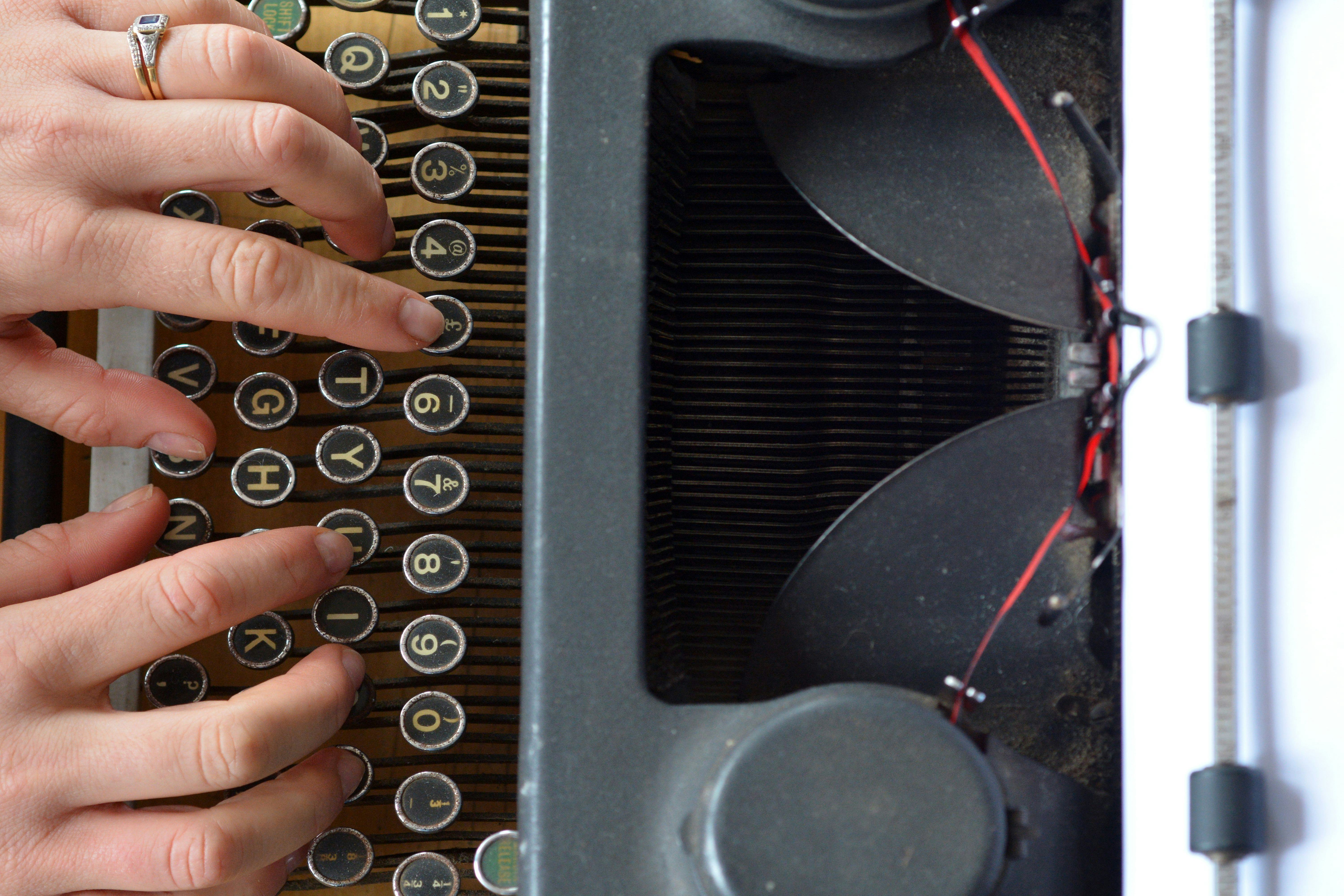 Hand of a young woman writer writing on antique typewriter. Above view - Type Writing Concept
