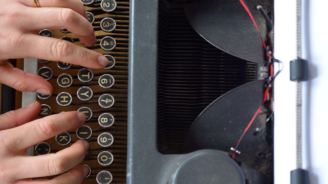 Hand of a young woman writer writing on antique typewriter. Above view - Type Writing Concept