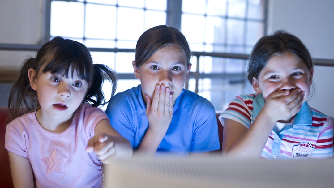 MODEL RELEASED Three little girls secretly watching a video
