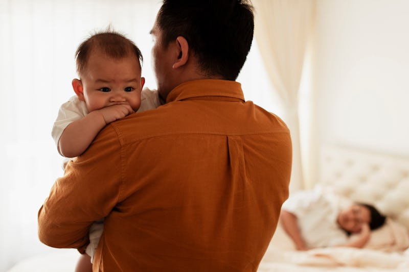 Father parenting son while mother has fallen asleep. Equal parental leave is emerging as a way to cl...