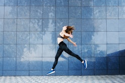 Young fitness woman dancing and jumping outdoors. Urban sport concept.