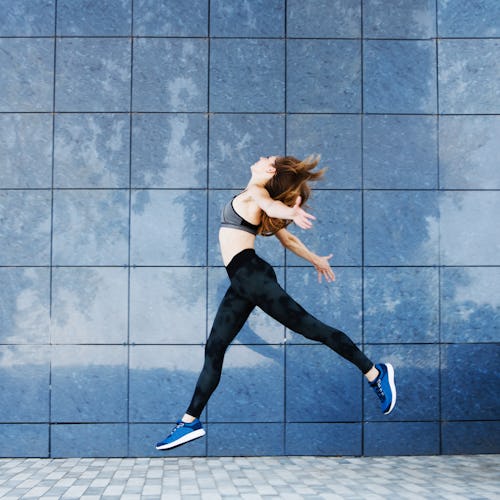 Young fitness woman dancing and jumping outdoors. Urban sport concept.
