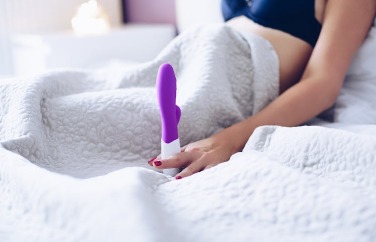 Young woman and sex toy dildo vibrator in bed