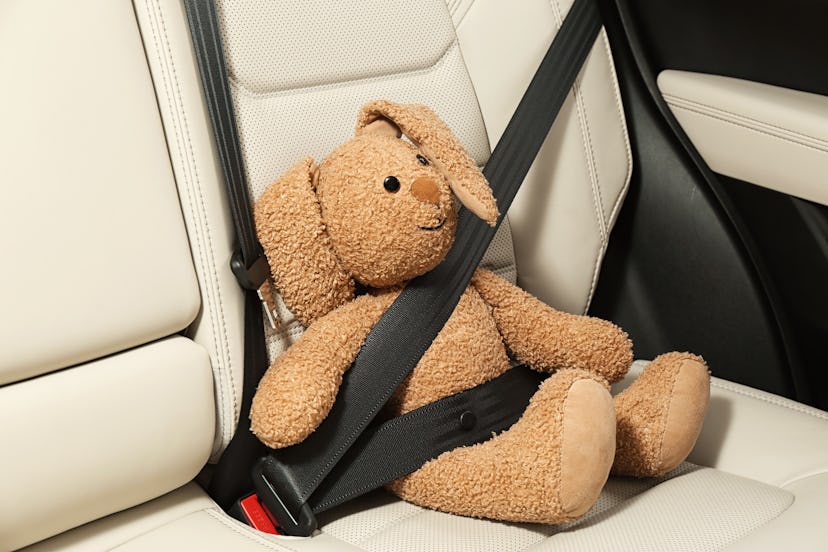 Cute stuffed toy rabbit buckled in backseat of car