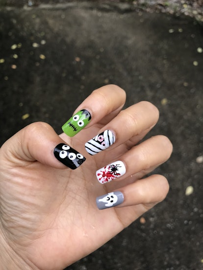 Long, square-shaped nails feature nail art that looks like eyeballs, Frankenstein's head, a mummy, a...