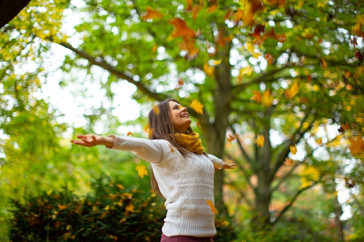 Young Woman smiling beautifully in a park with autumn leaves. Autumn season. Autumn background.