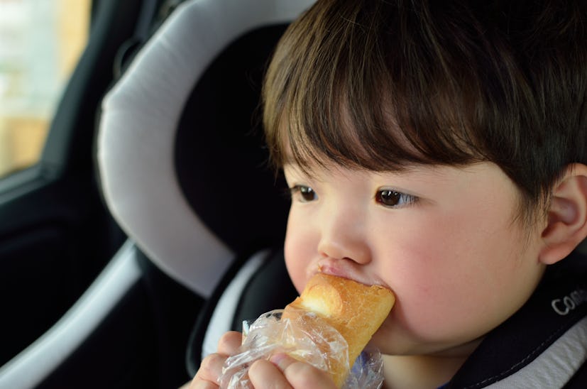 Child rides on a child seat and eats bread