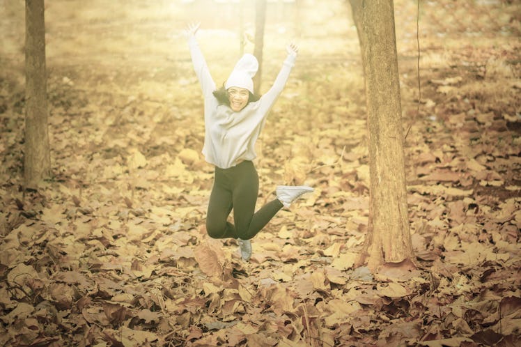 Picture of young man looks happy while jumping in the autumn park with dried autumn foliage