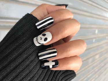 A woman's hand has black and white square-shaped nails decorated with inspirations from 'The Nightma...