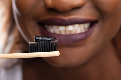 Close-up Of Young Woman Holding Tooth Brush With Black Active Charcoal Toothpaste