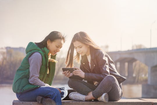 Two teenagers look at a phone together.