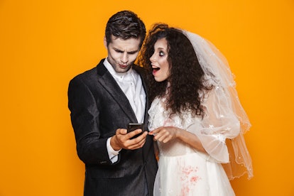 Photo of beautiful zombie couple bridegroom and bride wearing wedding outfit and halloween makeup us...