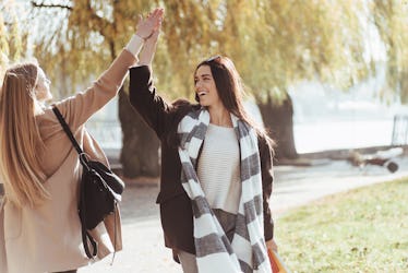 Give me the high five. Two young friends are glad to meet each other at park after the studying.