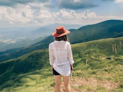 Woman in hat standing back. Mountains background
