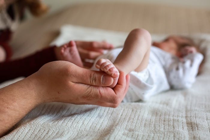 Dad holds baby's leg in his hands