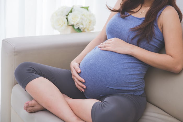 close up portrait of a pregnant stomach sitting on a couch