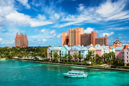 Beautiful scene of a boat, ocean, colorful houses and a hotel in Nassau, Bahamas on a summer sunny d...