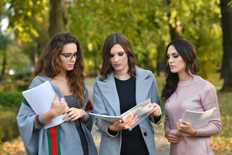 three student woman with textbook in a park in autumn