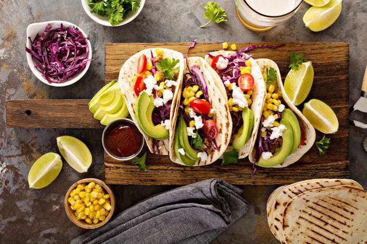 Pulled pork tacos with red cabbage, tomatoes, corn, feta and avocados overhead shot