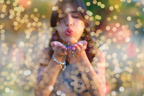 Young beautiful women blowing colorful confetti stars from hands. Celebration and event concept. Mom...