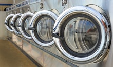 Row of industrial laundry machines in laundromat.