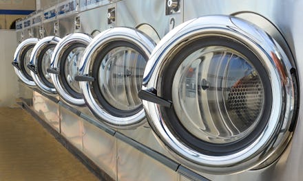 Row of industrial laundry machines in laundromat.