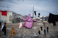 Clothes which belong to refugees drying on a fence, right on the borderline that splits Greece from ...