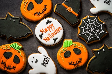 A spread of Halloween cookies, including ones decorated like ghosts, bats, witch hats, and pumpkins,...