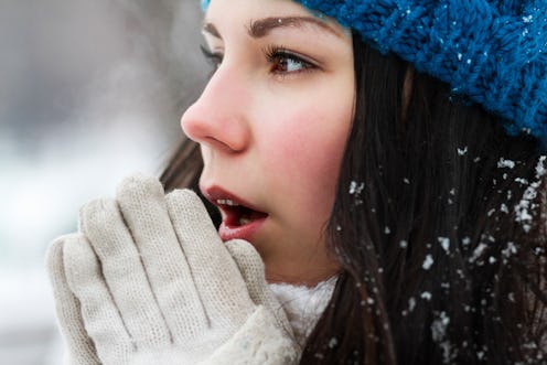 Girl feels cold outside.Portrait of frozen white brunette female in knit blue hat.Young woman breath...
