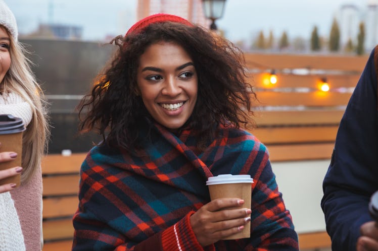 Image of a happy young girl drinking coffee outdoors winter concept.