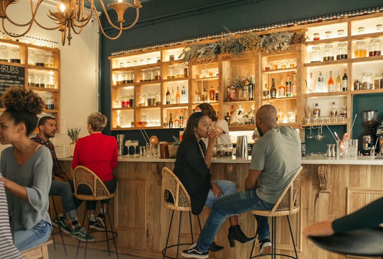 Smiling young African American couple sitting at the counter of a bar talking and having drinks whil...