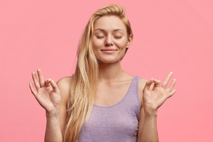 People, calmness concept. Adorable relaxed young female keeps eyes closed and fingers crossed, hopes...