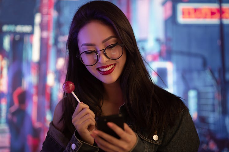 Asina girl using a smartphone in the city at night. Portrait of an attractive young woman having fun...