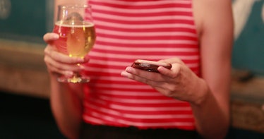 Woman holding beer and cellphone smartphone device at bar