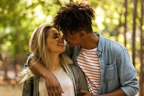 Lovely young multiethnic couple spending time together at the park, walking, hugging