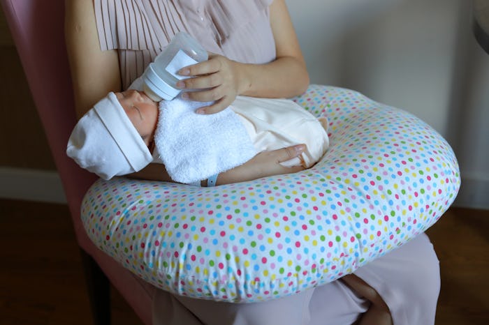 mom giving her baby a bottle, boppy on her lap