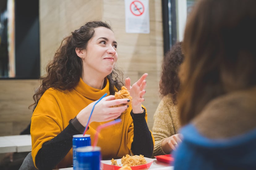 young caucasian woman eating in fast food with friends  - hungry, break, communication