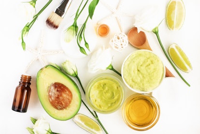 Homemade cosmetic mask with fresh avocado & green lime slices fruits, ingredients on white desktop, ...