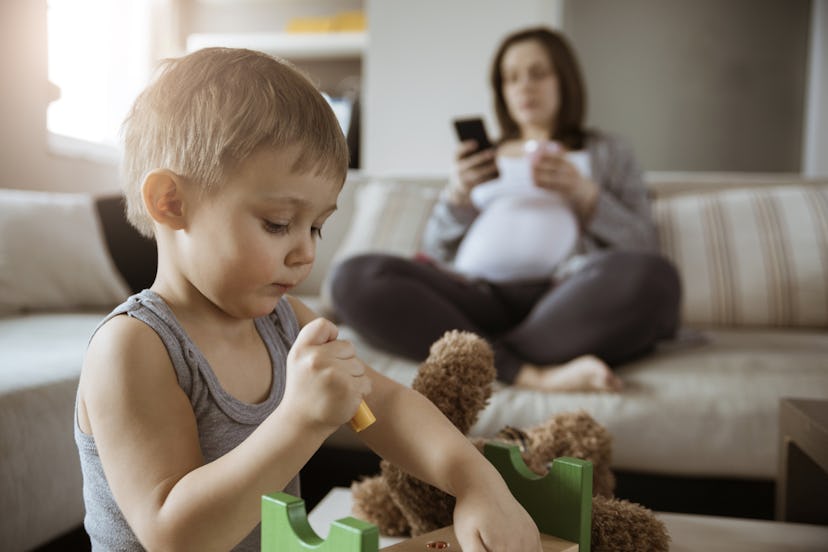 Little Cute Son Playing While His Pregnant Mom Is On The Phone