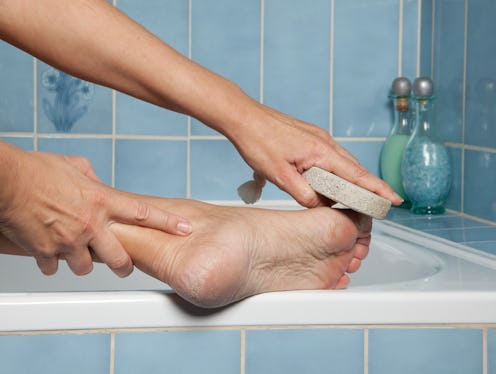 Hand removing callus from feet using pumice stone