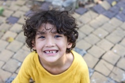 Curly hair mixed kid with natural loose tooth with toned color and lighting and selective focus
