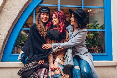 Young women hugging and laughing on city street. Best friends having good time together
