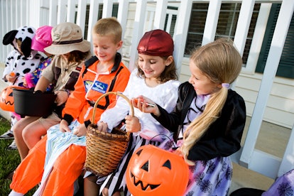 Halloween: Kids Sit On Porch And Look At Halloween Candy